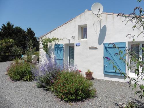 un edificio blanco con puertas azules y algunas plantas en Au Passage du Gois en Beauvoir-sur-Mer