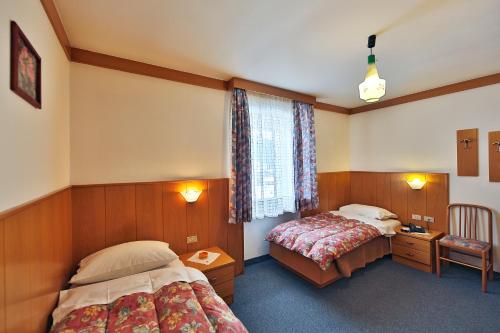 a hotel room with two beds and a window at Hotel Fiorenza in Campitello di Fassa