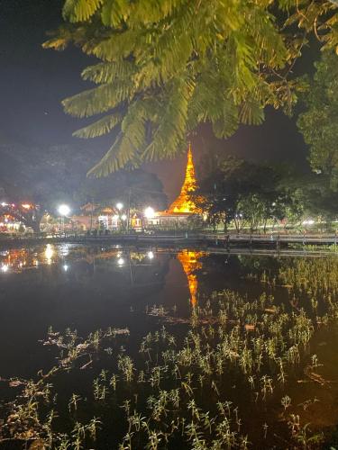 a pagoda lit up at night next to a body of water at Trinity Family Inn in Nyaung Shwe