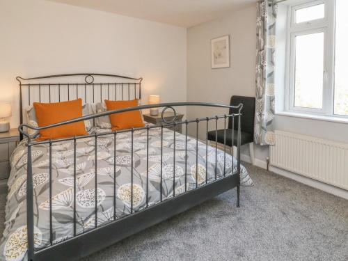 - une chambre avec un lit en métal et des oreillers orange dans l'établissement Kiln Cottage, à Ilfracombe