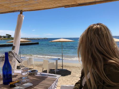 une femme assise à une table sur la plage dans l'établissement Villa Patrimoine, aux Issambres