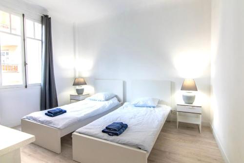 une chambre avec deux lits et deux lampes et une fenêtre dans l'établissement Résidence Estienne d'Orves, à Nice