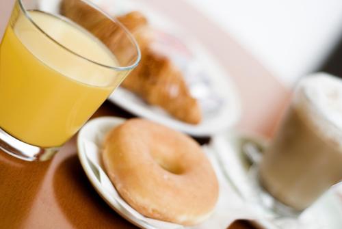 a plate of donuts and a glass of orange juice at Hotel Ciutat De Sant Adria in Sant Adria de Besos