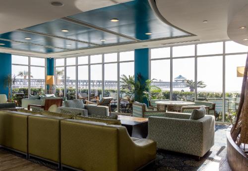 a lobby with couches and tables and large windows at Tides Folly Beach, Charleston's Oceanfront Hotel in Folly Beach