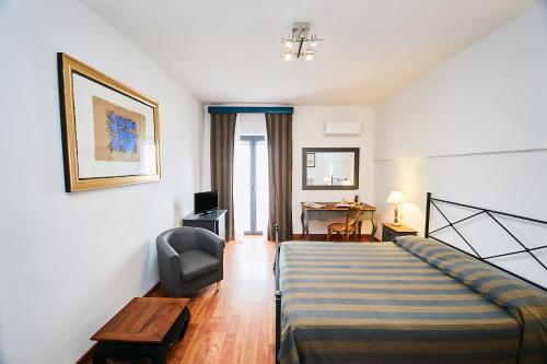 a bedroom with a bed and a chair and a desk at Hotel Enterprise in Montalto di Castro