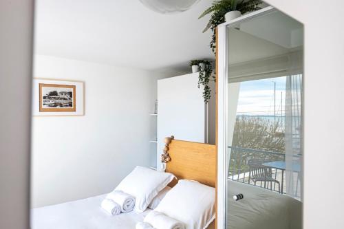 a bedroom with a mirror and a bed and a balcony at Hôtel La Reine Jane in Hyères