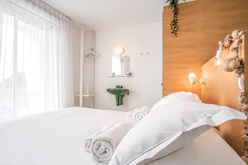 a bedroom with a white bed and a window at Hôtel La Reine Jane in Hyères