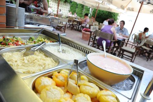 a buffet line with trays of food and a bowl of food at Hotel Minaret&Étterem in Eger