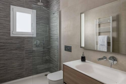 a bathroom with a sink and a toilet and a mirror at Kallia Sea Breeze - 3 Bedroom Apartment in Rhodes Town