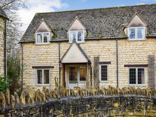 a stone house with a stone fence in front of it at Queen Mary in Winchcombe