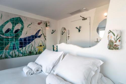 a bedroom with two beds and a painting on the wall at Hôtel La Reine Jane in Hyères