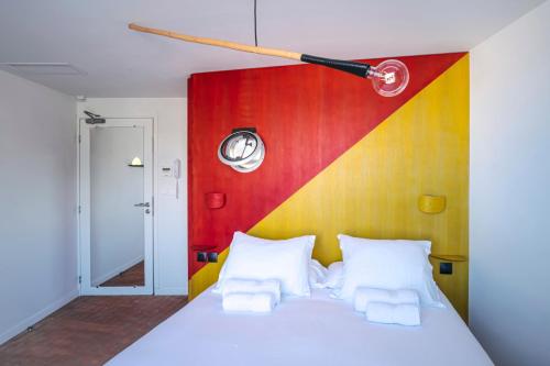 a bedroom with a white bed with a colorful wall at Hôtel La Reine Jane in Hyères