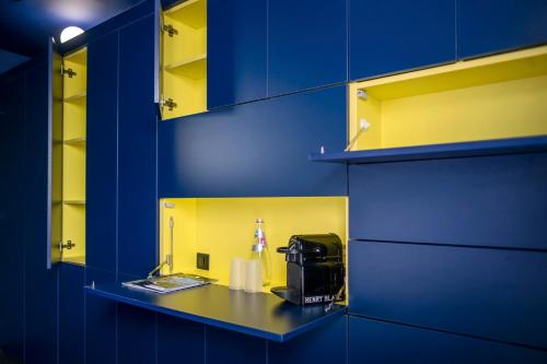 a blue and yellow room with a counter with a toaster at Hôtel La Reine Jane in Hyères