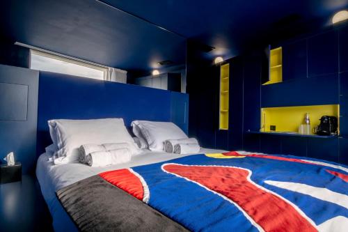 a blue room with a bed with a red white and blue blanket at Hôtel La Reine Jane in Hyères