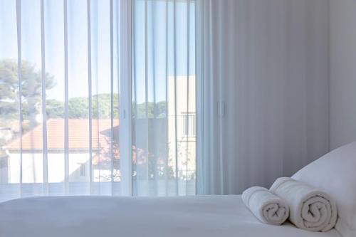 a white bedroom with a window with towels on a bed at Hôtel La Reine Jane in Hyères
