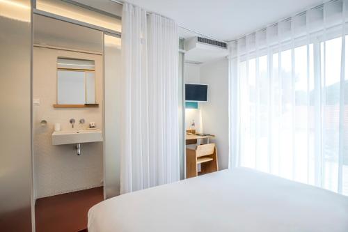 a bedroom with a white bed and a sink at Hôtel La Reine Jane in Hyères