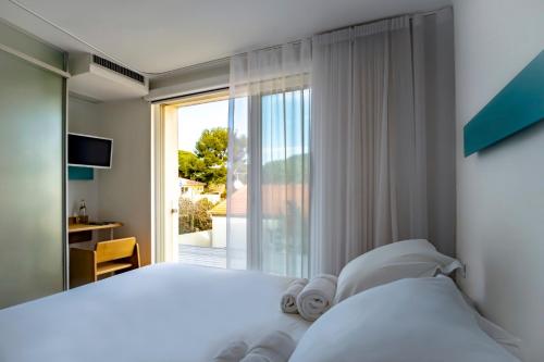 a bedroom with a bed and a large window at Hôtel La Reine Jane in Hyères