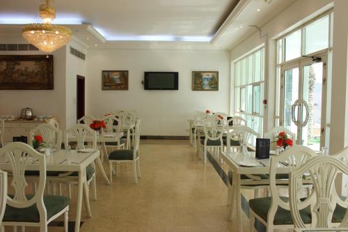 a dining room with white tables and white chairs at Royal Residence Hotel Apartments in Umm Al Quwain