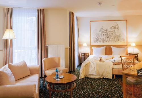 Habitación de hotel con cama y sala de estar. en Hotel Andreas en Dresden