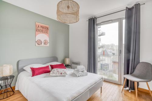 Cette chambre comprend un lit blanc avec des oreillers rouges et une fenêtre. dans l'établissement Le First by Cocoonr, à Nantes