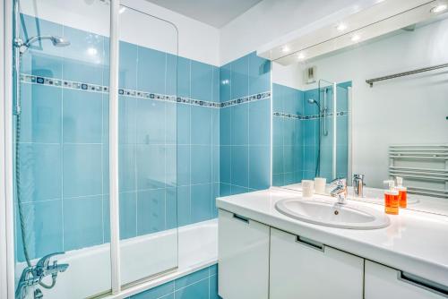La salle de bains bleue est pourvue d'un lavabo et d'une douche. dans l'établissement Le First by Cocoonr, à Nantes