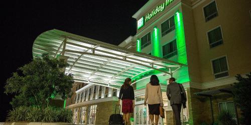 three people standing outside of a building with green lights at Holiday Inn - Long Island - ISLIP Arpt East by IHG in Holtsville