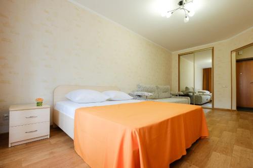 a bedroom with a bed with an orange sheet on it at OK! Советская 98 №1 in Tomsk