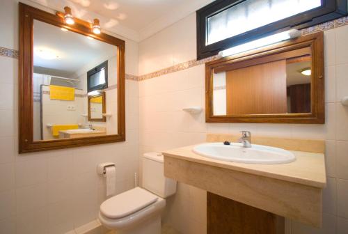 ein Badezimmer mit einem Waschbecken, einem WC und einem Spiegel in der Unterkunft 4 bedroom Villa Saturn with private heated pool in Puerto del Carmen