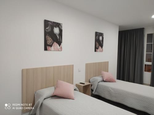 Santa Olallaにあるhostal la taurinaのピンクの枕が付くベッド2台が備わるホテルルームです。