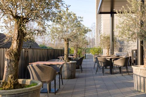 a patio with tables and chairs and trees at Mezzo Hotel & Business in Beringen