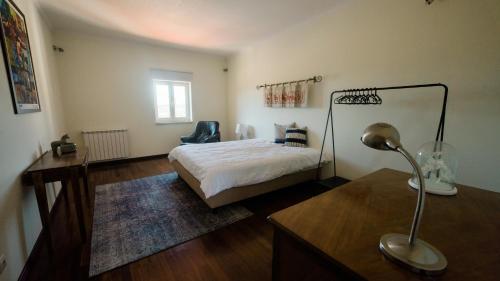a bedroom with a bed and a desk with a lamp at Quinta dos Lameiros in Vila Nova de Poiares