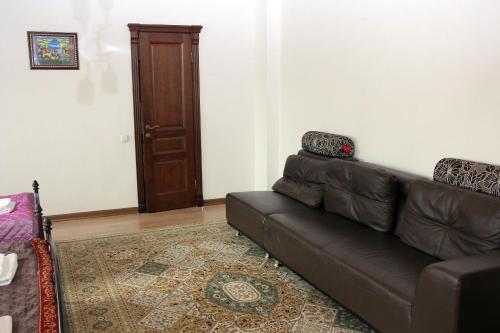 a living room with a brown couch and a door at Zhaylau Hotel in Shchūchīnsk