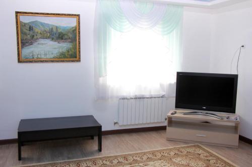 a living room with a flat screen tv and a window at Zhaylau Hotel in Shchūchīnsk