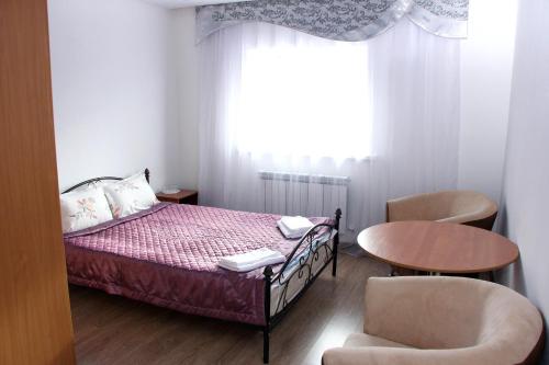 a bedroom with a bed and a table and a chair at Zhaylau Hotel in Shchūchīnsk