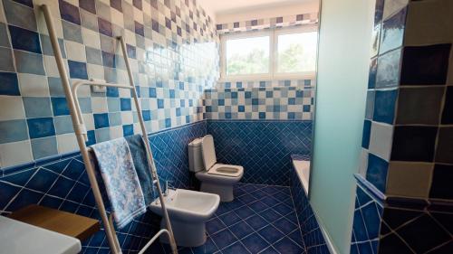 W wyłożonej niebieskimi kafelkami łazience znajduje się toaleta i umywalka. w obiekcie Quinta dos Lameiros w mieście Vila Nova de Poiares