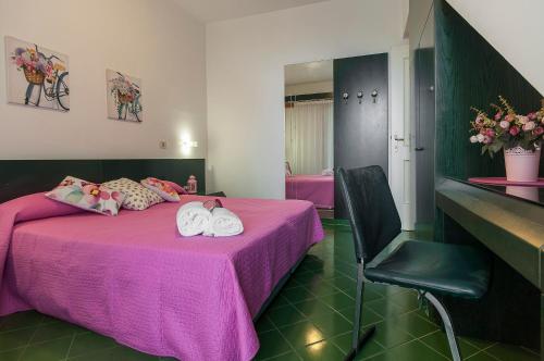 1 Schlafzimmer mit 2 Betten mit rosa Bettwäsche und einem Stuhl in der Unterkunft Casa Vacanza Kair Bilo 224 in Sperlonga