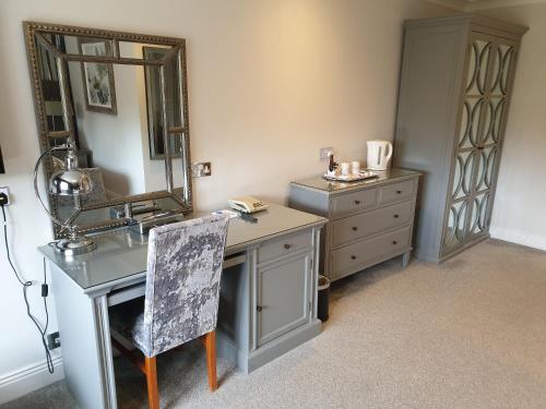 a bathroom with a sink and a mirror and a dresser at De Rougemont Manor in Brentwood