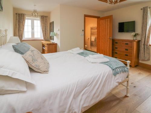 una camera da letto con un grande letto bianco e una televisione di Yr Hen Beudy ad Aberystwyth