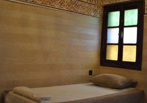 a bed with a pillow in a room with a window at Riad Dar Essassi 23 in Marrakech