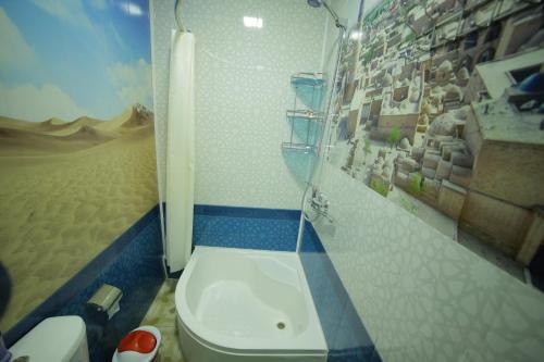a bathroom with a toilet and a picture of a desert at Fayz Guest House in Khiva