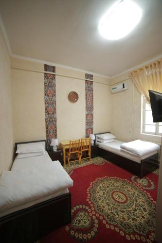 a hotel room with two beds and a window at Fayz Guest House in Khiva