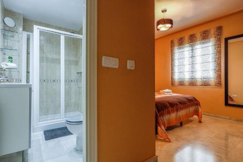 a bathroom with orange walls and a toilet and a bed at Sensacional Apt 2 Hab 2 baños 4 pax Aljarafe Metro in San Juan de Aznalfarache