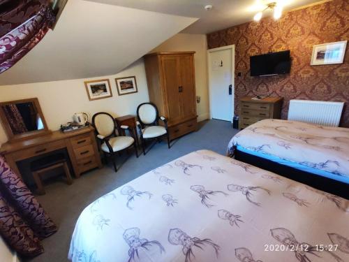 a hotel room with two beds and a television at The Lodge Guest House in Elgin