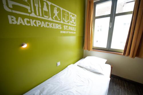 ein Schlafzimmer mit einem Bett mit einer grünen Wand und einem Fenster in der Unterkunft Backpackers St. Pauli in Hamburg