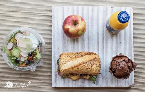 NotaBene Wola Apartment في وارسو: شطيرة وتفاحة وكوب من عصير البرتقال