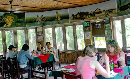 un grupo de personas sentadas en mesas en un restaurante en Eden jungle resort, en Sauraha