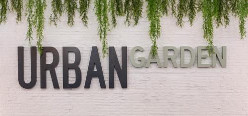 a sign on a white brick wall with green plants at Clement Barajas in Madrid