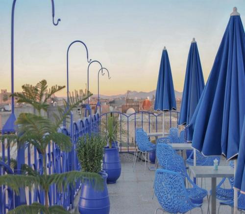 um grupo de cadeiras e mesas azuis e guarda-sóis em Riad Dar Essassi 23 em Marrakech