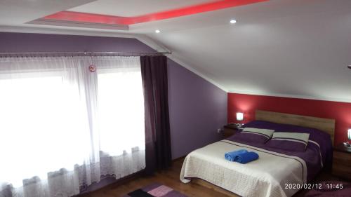 a bedroom with a bed with purple walls and windows at Apartament w domu na wsi in Tomaszów Lubelski