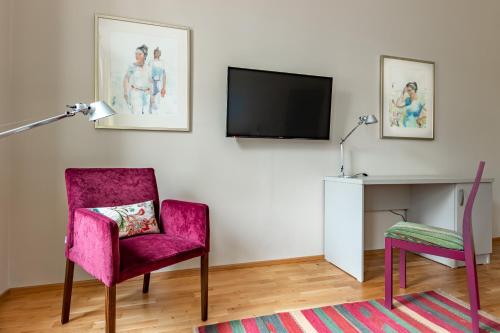 a living room with a pink chair and a tv at Boutique Hotel SwissHouse in Mariánské Lázně